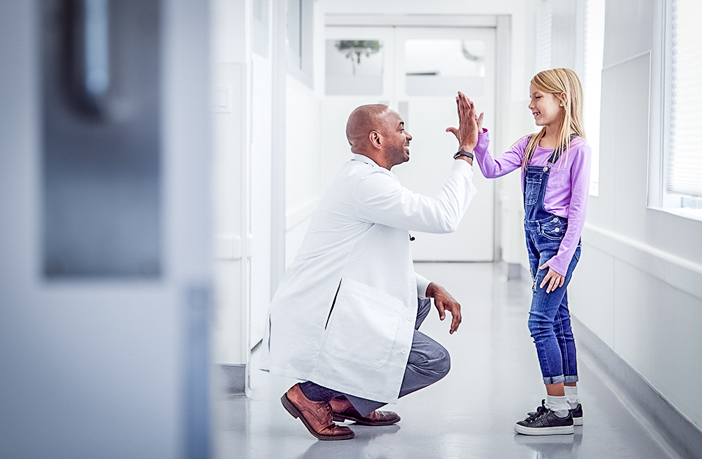 Hospital doctor high-fiving young girl
